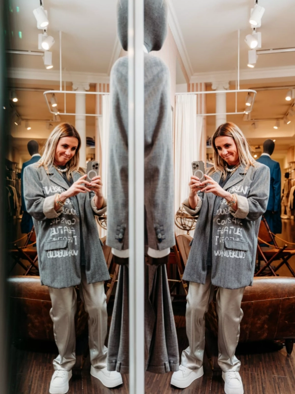 Eine Frau in einem modernen Business-Outfit, die selbstbewusst in die Kamera blickt. Ihr Lächeln unterstreicht Professionalität und Stil.