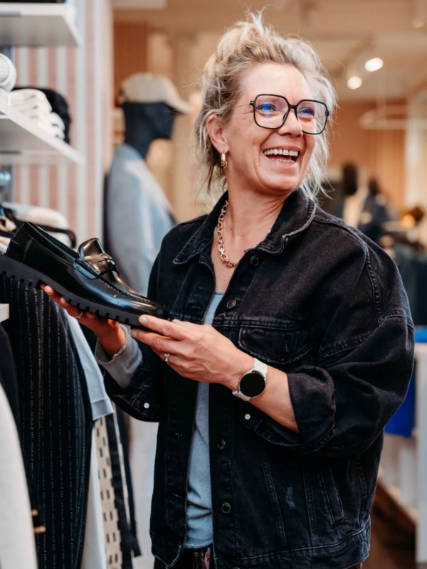 Eine Frau in einem eleganten, modernen Business-Outfit lächelt selbstbewusst in die Kamera. Ihr souveränes Auftreten vermittelt Professionalität und Stil